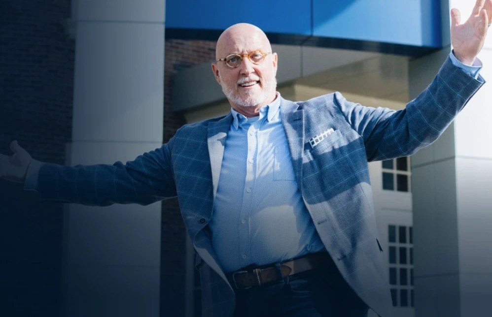 Man in blue suit extending arms outside building